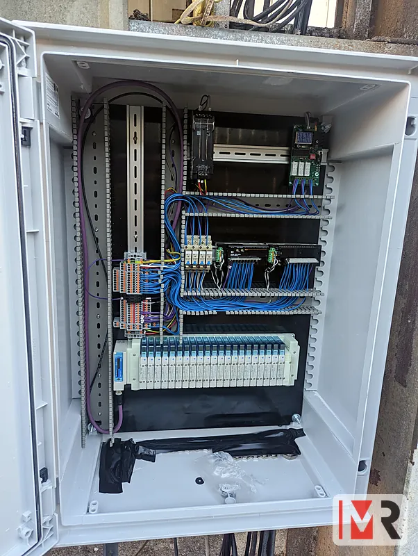 Outdoor control panel with PLC, relays and terminal rows, blue control wiring